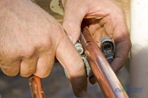 Man-Cutting-Copper-Pipe A Man is Cutting a Copper Pipe To Work with it.