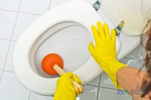 a clogged toilet is cleaned. with yellow latex gloves. for toilet repair.
